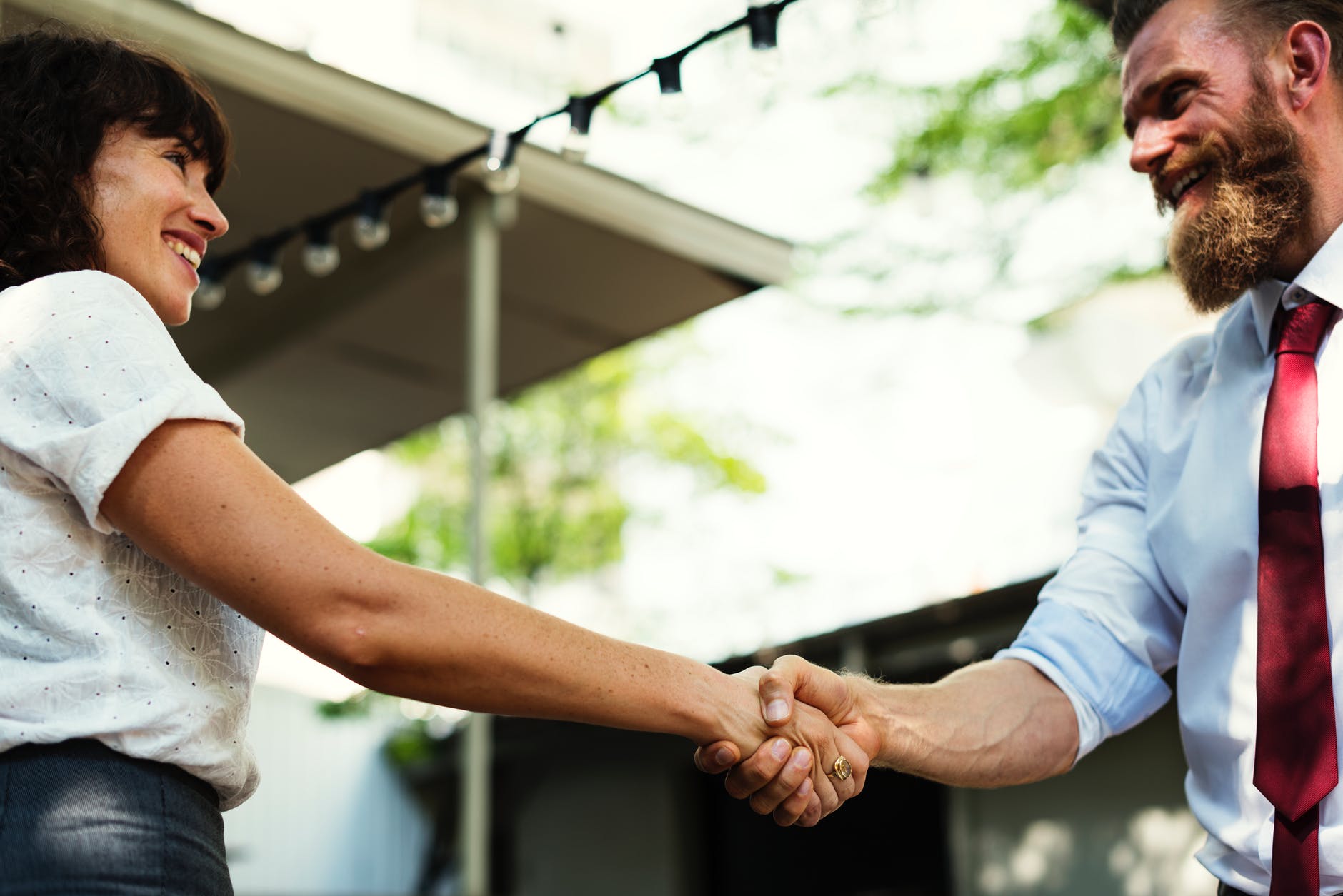 man in white dress shirt and maroon necktie holding hands with girl in white dress