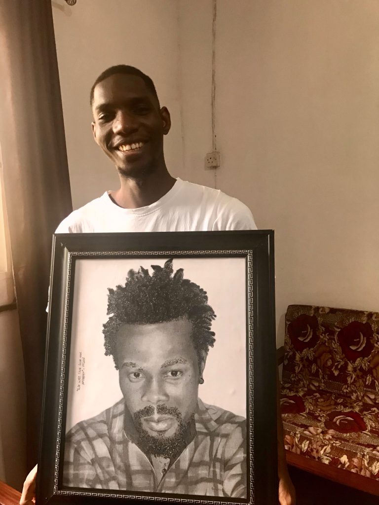 Dick David holding an art portrait of David Ifeanyi