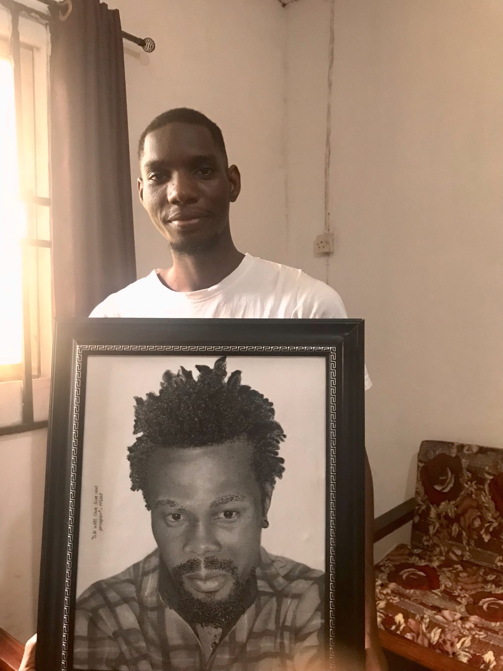 Dick David holding an art portrait of David Ifeanyi